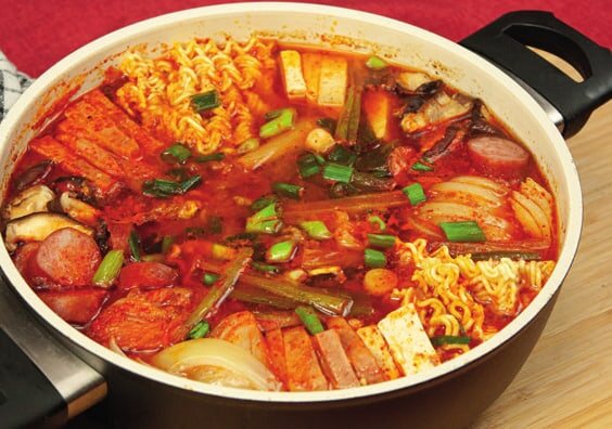 Fertiges Budae-Jjigae im Topf, von der Seite fotografiert