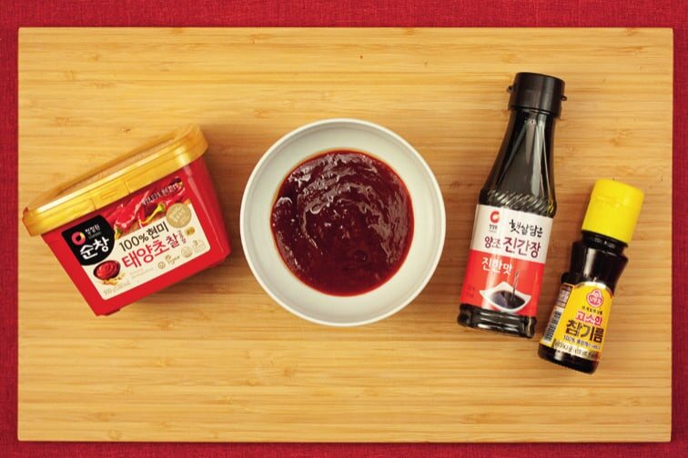 Schale mit roter Soße, daneben Gochujang, Sojasoße und Sesamöl