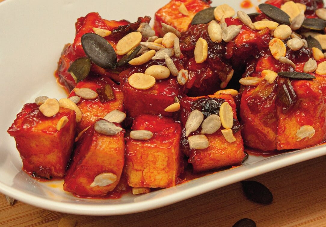 Glasierte rote Tofuwürfel mit Kürbiskernen, Sonnenblumenkernen und Erdnüssen, Nahaufnahme